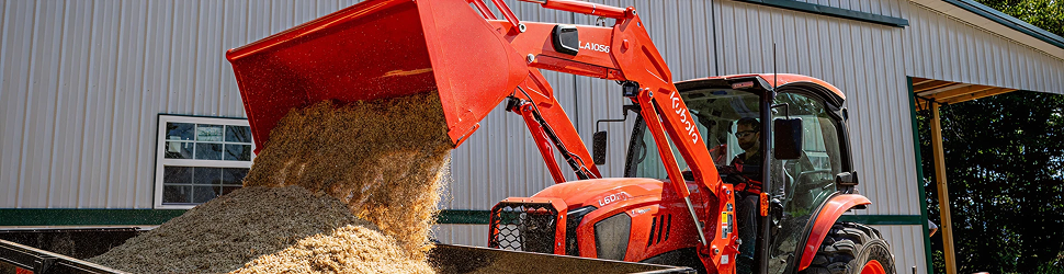 Kubota compact tractor dumping dirt into a bin